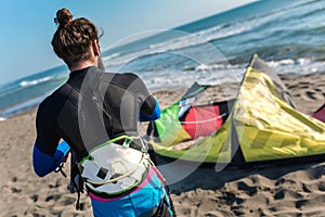 Sufrers in wetsuits with kite equipment for surfing.