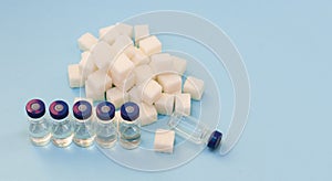 Sugar addiction, insulin resistance, unhealthy diet, sugar cubes and bottles of insulin on blue background, diabetes protection