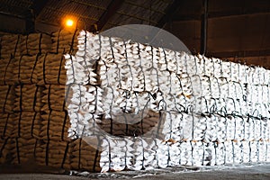 Sugar bags stack in pile inside warehouse for export.