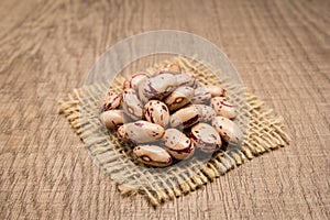 Sugar Bean legume. Grains on square cutout of jute. Wooden tabl photo