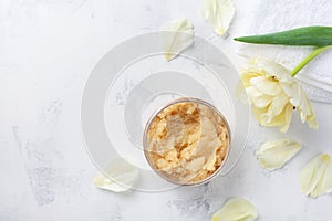 Sugar body scrub in glass jar on white stone table. Homemade cosmetic for spa