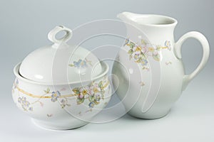 Sugar bowl and milk jug with flowers on white background photo