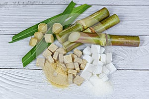 Sugar cane with brown and white sugar cubes on wood background / Close up Sugarcane