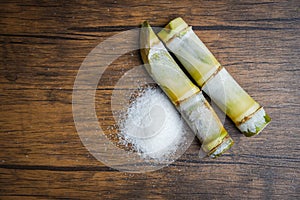 Sugar cane and white sugar rustic wood background top view