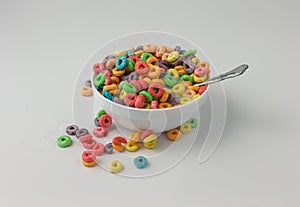 Sugar coated fruity flavored cereal in a bowl with milk and spoon