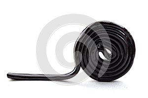 Sugar confectionery sweets and sweet candy concept with one black licorice or liquorice wheel or spiral isolated on white