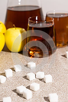 Sugar content in fruit juices. Sugar cubes and glasses of apple juice.