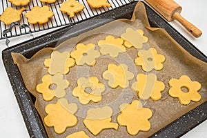 Sugar cookies in cute flower shapes close up on baking sheet.