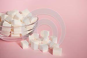 Sugar cubes in glass bowl on pink background