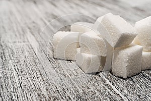 Sugar cubes lie on a wooden background of gray color