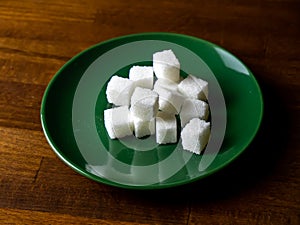 Sugar cubes on a plate and on a wooden table
