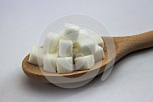 Sugar Cubes on Spoon on Isolated White Background with Harsh Shadow, which can be used to imply dark side of Sugar.