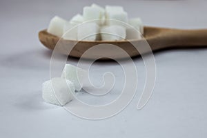 Sugar Cubes on Spoon on Isolated White Background with Harsh Shadow, which can be used to imply dark side of Sugar.