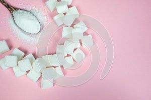 Sugar cubes and sugar in a spoon on a pink background.Sugar with copy space