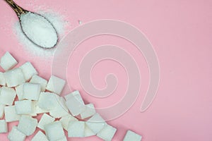 Sugar cubes and sugar in a spoon on a pink background.Sugar with copy space