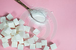 Sugar cubes and sugar in a spoon on a pink background.Sugar with copy space