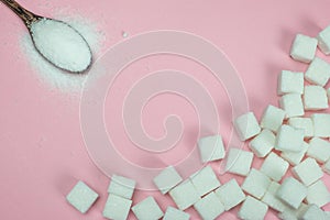 Sugar cubes and sugar in a spoon on a pink background.Sugar with copy space