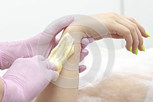 Sugar depilation cosmetic procedure applying shugaring paste on skin arm