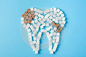 Sugar destroys the tooth enamel and leads to tooth decay. Tooth made of white and caries made of brown sugar cubes.