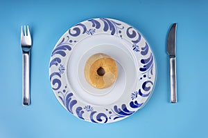 Sugar donuts on plate and cutlery on blue background