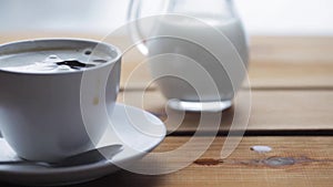 Sugar falling into cup of coffee on wooden table