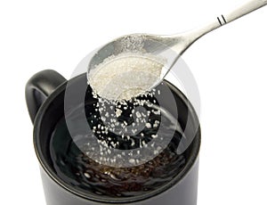 Sugar falling from spoon into a cup