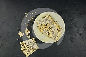 A sugar-free whole-grain flour on a light plate of sesame and flax seeds. top view. black background