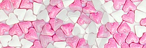 Sugar hearts colored white and pink, panorama background
