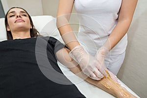 Sugar paste hair removal procedure - shugaring. Cosmetologist applies sugar paste to the hand of a young woman