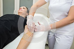 Sugar paste hair removal procedure - shugaring. Cosmetologist applies sugar paste to the hand of a young woman