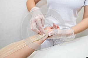 Sugar paste hair removal procedure - shugaring. Cosmetologist applies sugar paste to the hand of a young woman