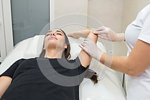 Sugar paste hair removal procedure - shugaring. Cosmetologist applies sugar paste to the hand of a young woman