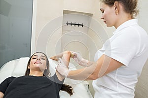 Sugar paste hair removal procedure - shugaring. Cosmetologist applies sugar paste to the hand of a young woman