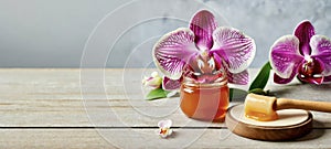 Sugar paste or wax honey for hair removing flows down from wooden waxing spatula sticks in jar with orchid flower