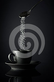 Sugar is poured into a cup of coffee