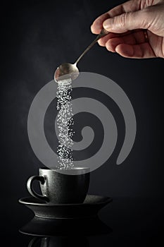 Sugar is poured into a cup of coffee