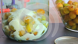 sugar is poured into a glass jar with yellow plums, preparation of compote for storage for the winter