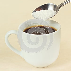 Sugar is poured from a spoon in coffee cup