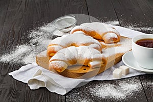 Sugar powder is poured onto a freshly baked croissan