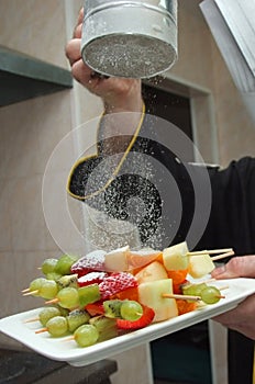 Sugar powder pouring over fruit plate