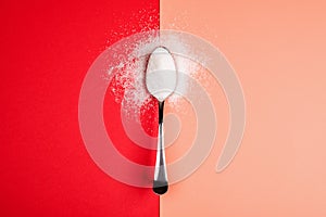 Sugar with spoon on red and yellow background