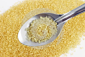 Sugar in spoon, sugarcane on spoon stainless steel and granulated sugar yellow background concept of Half a tablespoon granulate