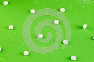 Sugar substitute pills and natural sweetener in powder on a green podium texture background