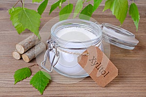 Sugar substitute xylitol, a glass jar with birch sugar, liefs and wood photo