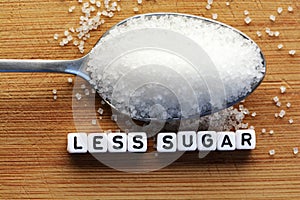 Less sugar text from tiled letter blocks and sugar pile on a spoon suggesting dieting concept photo