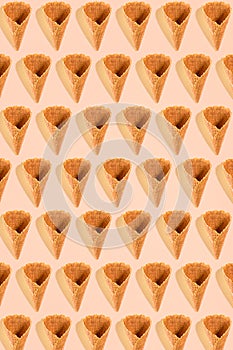 Sugar waffle cone for ice cream arranged in pattern on pink background. The image with copy space can be used as a