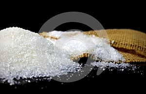 Sugar. White sugar. Spilled sugar. A pile of sugar and scattered sugar. White sugar on a black background.