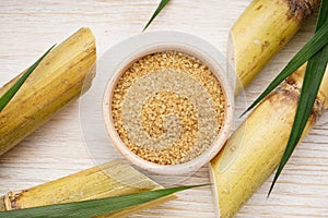 Sugarcane and brown sugar on a wooden background, close-up. Top view
