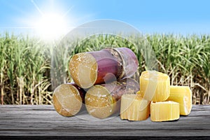 Sugar cane cut heap on wood plank and blurred sugarcane field plantation background, sugarcane fresh cut on wood