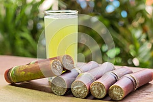 Sugarcane juice with piece of sugarcane on wooden background